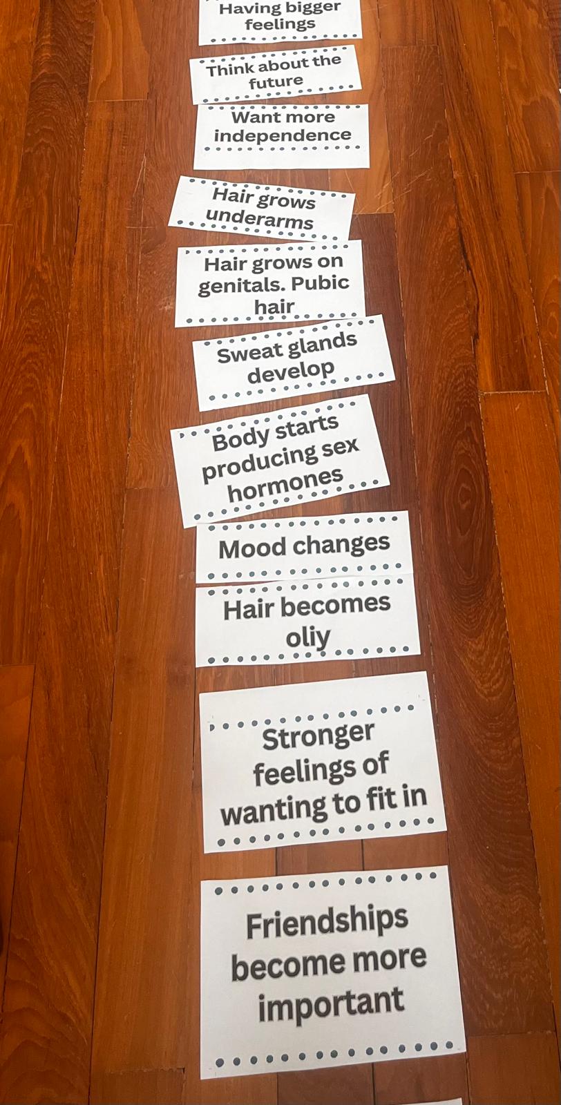 Puberty change cards sorted into columns on a classroom floor